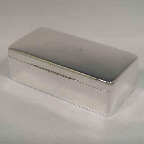 A very handsome Antique Sterling Silver cigarette / cigar table box, having a plain rectangular body with nice rounded corners, a hinged lid having an applied thumb-piece, with a gold-gilt and cedar wood-lined interior to the base, with a removable divider. This elegant antique silver table box was made by Robert Comyns of Birmingham in 1918. The dimensions of this fine hand-made antique silver table cigar or cigarette box are length 18 cms (7 inches), width 9 cms (3.5 inches), and height 6 cms (2.3 inches).   