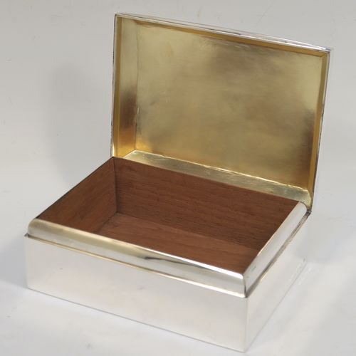 A very elegant Antique Sterling Silver cigarette / cigar table box, having a plain rectangular body, a hinged lid having an applied thumb-piece and chamfered edges, with a gold-gilt and cedar wood-lined interior to the base. This handsome antique silver table box was made by A. and J. Zimmerman of Birmingham in 1912. The dimensions of this fine hand-made antique silver table cigar or cigarette box are length 13.5 cms (5.3 inches), width 10 cms (4 inches), and height 5.5 cms (2.25 inches).  