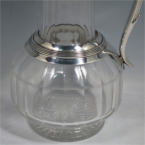 An Antique Victorian Silver Plated and hand-cut crystal claret jug, having a plain round mount with applied reeded borders, a stepped lid with a hand-pierced thumb-piece, a flat-topped scroll handle attached to a round and reeded security ring, together with a hand-cut round, panelled, and bellied crystal body with star-cut base. Made by William Hutton and Sons of Sheffield in 1880. The dimensions of this fine hand-made antique silver plated and crystal claret jug are height 24 cms (9.5 inches), and length 15 cms (6 inches).    