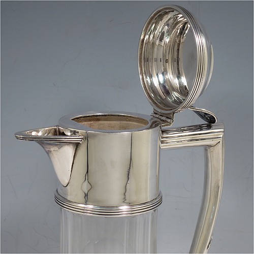 An Antique Victorian Silver Plated and hand-cut crystal claret jug, having a plain round mount with applied reeded borders, a stepped lid with a hand-pierced thumb-piece, a flat-topped scroll handle attached to a round and reeded security ring, together with a hand-cut round, panelled, and bellied crystal body with star-cut base. Made by William Hutton and Sons of Sheffield in 1880. The dimensions of this fine hand-made antique silver plated and crystal claret jug are height 24 cms (9.5 inches), and length 15 cms (6 inches).    