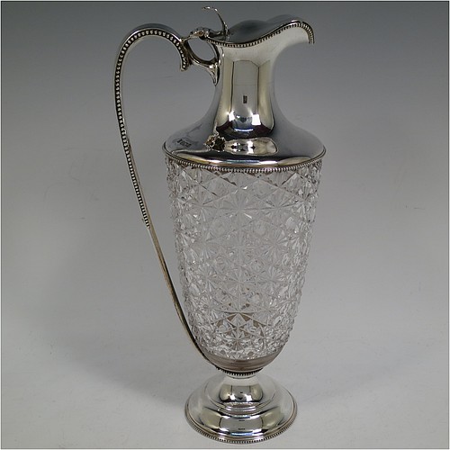 A very beautiful Antique Edwardian Sterling Silver and hand-cut crystal claret jug, having a round vase-shaped body with a plain round mount and applied bead-edged borders, a hinged lid with a hand-pierced thumb-piece over a spout with gold-gilt interior, a beaded and scroll side-handle, a hand-cut hobnail and star pattern main body, and all sitting on a round and stepped pedestal foot. Made by Walter and Charles Sissons of Sheffield in 1905. The dimensions of this fine hand-made antique silver and crystal claret jug are height 29 cms (11.5 inches), and length 13.5 cms (5.3 inches).   