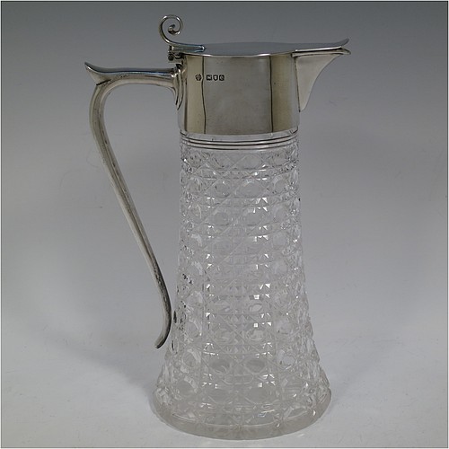 A very handsome Antique Victorian Sterling Silver and hand-cut crystal claret jug, having a plain oval mount, a hinged flat lid with scroll finial, a plain scroll handle with thumb-piece, together with a hand-cut Hobnail pattern oval body with straight tapering sides, and with a star-cut flat base. Made by William Hutton and Sons of London in 1900. The dimensions of this fine hand-made antique silver and crystal claret jug are height 27 cms (10.75 inches), and length 16.5 cms (6.5 inches).    