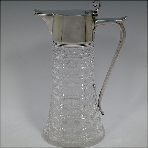 A very handsome Antique Victorian Sterling Silver and hand-cut crystal claret jug, having a plain oval mount, a hinged flat lid with scroll finial, a plain scroll handle with thumb-piece, together with a hand-cut Hobnail pattern oval body with straight tapering sides, and with a star-cut flat base. Made by William Hutton and Sons of London in 1900. The dimensions of this fine hand-made antique silver and crystal claret jug are height 27 cms (10.75 inches), and length 16.5 cms (6.5 inches).    