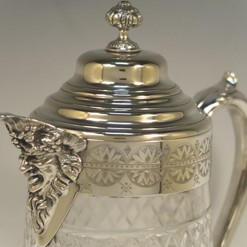 A very handsome and large Antique Victorian Silver Plated and hand-cut crystal claret jug, having a hand-engraved mount with floral decoration, a Bacchus face on the spout, a hinged stepped and domed lid with cast finial, a scroll side handle attached to a lower strengthening girdle, and a round hand-cut straight-sided body with a single band of hand-engraved frosted cut work in a grapevine pattern with two bands of hobnail pattern above and below, all sitting on a flat base with a star-cut. Made in ca.1880. The dimensions of this fine hand-made antique silver-plated and crystal claret jug are height 29 cms (11.5 inches), length 20 cms (8 inches), and diameter at the base is 13 cms (5 inches). 