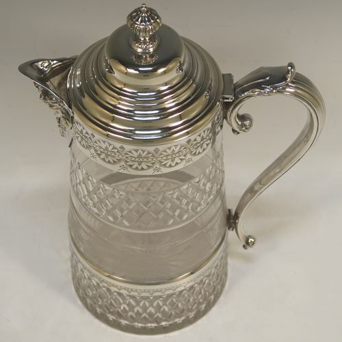 A very handsome and large Antique Victorian Silver Plated and hand-cut crystal claret jug, having a hand-engraved mount with floral decoration, a Bacchus face on the spout, a hinged stepped and domed lid with cast finial, a scroll side handle attached to a lower strengthening girdle, and a round hand-cut straight-sided body with a single band of hand-engraved frosted cut work in a grapevine pattern with two bands of hobnail pattern above and below, all sitting on a flat base with a star-cut. Made in ca.1880. The dimensions of this fine hand-made antique silver-plated and crystal claret jug are height 29 cms (11.5 inches), length 20 cms (8 inches), and diameter at the base is 13 cms (5 inches). 