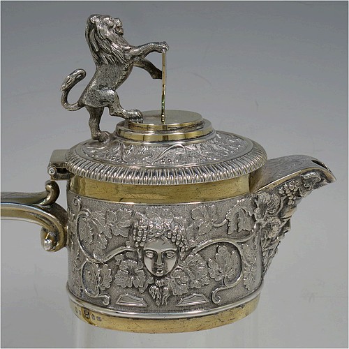 A very handsome Antique Victorian Silver Plated and hand-cut crystal claret jug, having an ornate parcel gilt Bacchus style round mount with hand-chased grapevine work, a sided handle with a bead-edged security ring, a hinged lid with a cast rampant lion and shield finial, together with a hand-cut crystal round body with straight sides and a tucked under belly above a flat star-cut base. Made by Elkington and Co., of Sheffield, with a date letter for 1883. The dimensions of this fine hand-made antique silver-plated and crystal claret jug are height 27 cms (10.5 inches), and length 16 cms (6.25 inches). Please note that this item is monogrammed on the finial shield.    