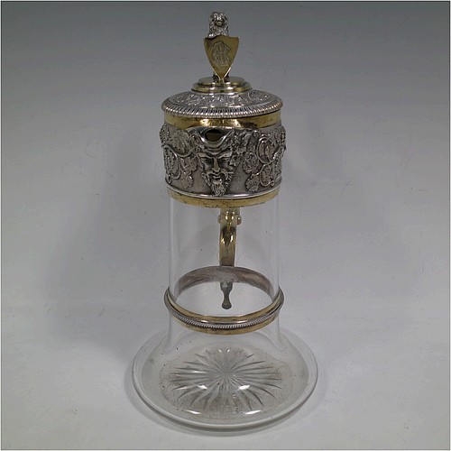 A very handsome Antique Victorian Silver Plated and hand-cut crystal claret jug, having an ornate parcel gilt Bacchus style round mount with hand-chased grapevine work, a sided handle with a bead-edged security ring, a hinged lid with a cast rampant lion and shield finial, together with a hand-cut crystal round body with straight sides and a tucked under belly above a flat star-cut base. Made by Elkington and Co., of Sheffield, with a date letter for 1883. The dimensions of this fine hand-made antique silver-plated and crystal claret jug are height 27 cms (10.5 inches), and length 16 cms (6.25 inches). Please note that this item is monogrammed on the finial shield.    