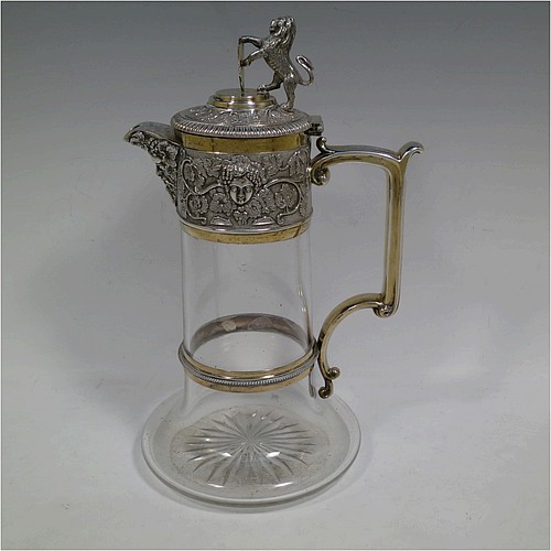 A very handsome Antique Victorian Silver Plated and hand-cut crystal claret jug, having an ornate parcel gilt Bacchus style round mount with hand-chased grapevine work, a sided handle with a bead-edged security ring, a hinged lid with a cast rampant lion and shield finial, together with a hand-cut crystal round body with straight sides and a tucked under belly above a flat star-cut base. Made by Elkington and Co., of Sheffield, with a date letter for 1883. The dimensions of this fine hand-made antique silver-plated and crystal claret jug are height 27 cms (10.5 inches), and length 16 cms (6.25 inches). Please note that this item is monogrammed on the finial shield.    