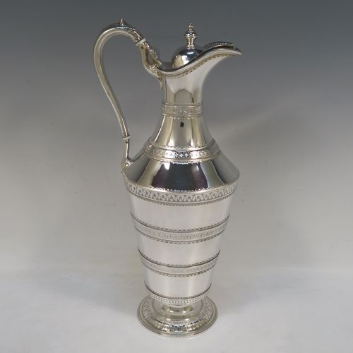 A very unusual Antique Victorian Silver Plated  claret or water jug ewer, having a round body with tapering sides and bands of hand-engraved floral and geometric decoration, an insulated side handle, a hinged lid with an urn finial, and all sitting on a pedestal foot. This beautiful antique silver-plated ewer was made in ca. 1880. The dimensions of this fine hand-made antique silver-plated claret jug are height 32 cms (12.5 inches), and length 15 cms (6 inches).   