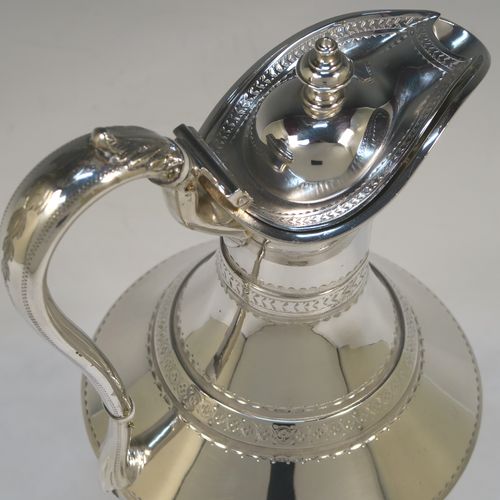 A very unusual Antique Victorian Silver Plated  claret or water jug ewer, having a round body with tapering sides and bands of hand-engraved floral and geometric decoration, an insulated side handle, a hinged lid with an urn finial, and all sitting on a pedestal foot. This beautiful antique silver-plated ewer was made in ca. 1880. The dimensions of this fine hand-made antique silver-plated claret jug are height 32 cms (12.5 inches), and length 15 cms (6 inches).   