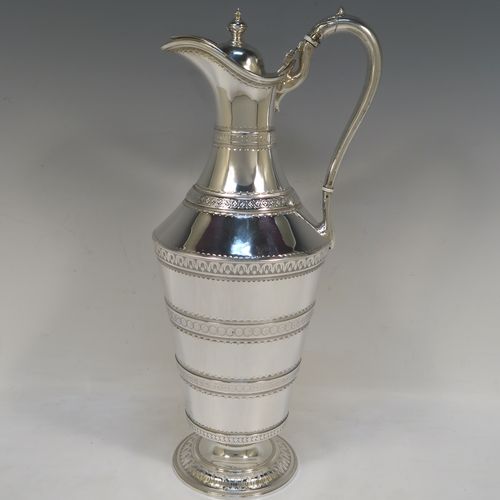 A very unusual Antique Victorian Silver Plated  claret or water jug ewer, having a round body with tapering sides and bands of hand-engraved floral and geometric decoration, an insulated side handle, a hinged lid with an urn finial, and all sitting on a pedestal foot. This beautiful antique silver-plated ewer was made in ca. 1880. The dimensions of this fine hand-made antique silver-plated claret jug are height 32 cms (12.5 inches), and length 15 cms (6 inches).   