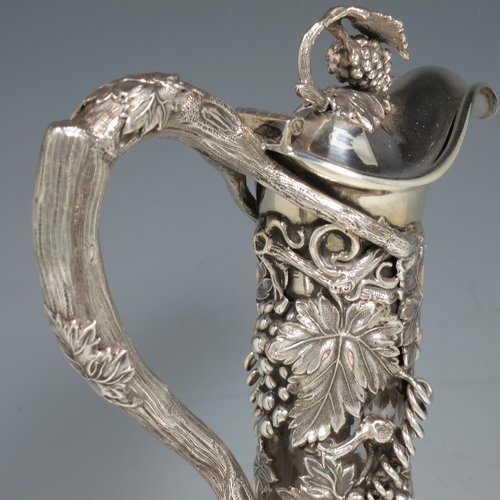 An Antique Victorian Sterling Silver and hand-cut crystal claret jug, having a cast grape and vine leaf mount on a hobnail-cut crystal round baluster body. with cast scroll vine tendril handle, a hinged lid with cast finial, and sitting on a flat star-cut base. Made by Cartwright & Woodward of Birmingham in 1860. The dimensions of this fine hand-made antique silver and crystal claret jug are height 31 cms (12.25 inches), and diameter at base 14 cms (5.5 inches).    