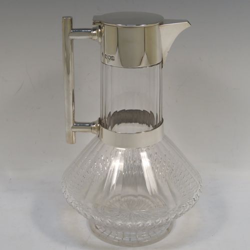 A very handsome Antique Victorian Sterling Silver and hand-cut crystal claret jug in an Arts and Crafts style, having a plain round mount, a flat hinged lid, a plain geometrical straight handle with lower strengthening ring, together with a hand-cut round and panelled crystal body with lower hobnail cut and star-cut base. This beautiful silver and crystal claret jug was made by the Mappin Brothers of London in 1898. The dimensions of this fine hand-made antique silver and crystal claret jug are height 22 cms (8.75 inches), and length 14 cms (5.5 inches).  