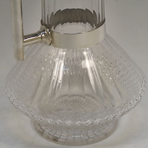 A very handsome Antique Victorian Sterling Silver and hand-cut crystal claret jug in an Arts and Crafts style, having a plain round mount, a flat hinged lid, a plain geometrical straight handle with lower strengthening ring, together with a hand-cut round and panelled crystal body with lower hobnail cut and star-cut base. This beautiful silver and crystal claret jug was made by the Mappin Brothers of London in 1898. The dimensions of this fine hand-made antique silver and crystal claret jug are height 22 cms (8.75 inches), and length 14 cms (5.5 inches).  