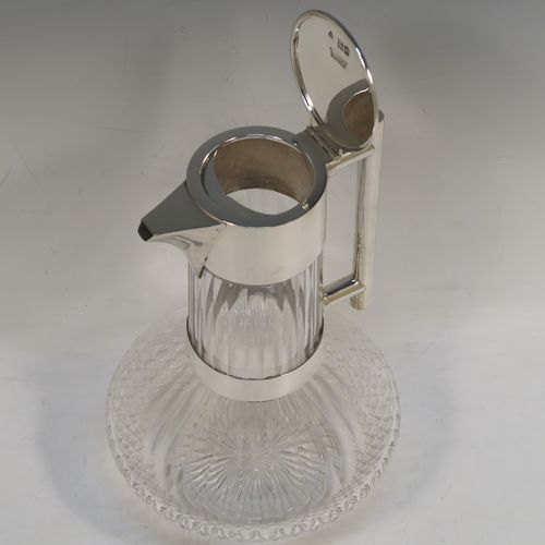 A very handsome Antique Victorian Sterling Silver and hand-cut crystal claret jug in an Arts and Crafts style, having a plain round mount, a flat hinged lid, a plain geometrical straight handle with lower strengthening ring, together with a hand-cut round and panelled crystal body with lower hobnail cut and star-cut base. This beautiful silver and crystal claret jug was made by the Mappin Brothers of London in 1898. The dimensions of this fine hand-made antique silver and crystal claret jug are height 22 cms (8.75 inches), and length 14 cms (5.5 inches).  