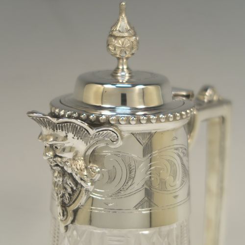 A very pretty Antique Victorian Silver Plated and hand-cut crystal claret jug, having a hand-engraved mount with scroll decoration, a Bacchus face on the spout, a hinged domed lid with a bead border and cast finial, a scrolled cast handle, a round hand-cut crystal body with tapering sides and a hobnail fluted panel pattern, all sitting on a flat star-cut base. Made by Mappin and Webb in there Princes Plate in ca. 1890. The dimensions of this fine hand-made antique silver-plated and crystal claret jug are height 28.5 cms (11.25 inches), length 14 cms (5.5 inches), and diameter at base is 11.5 cms (4.5 inches)..  