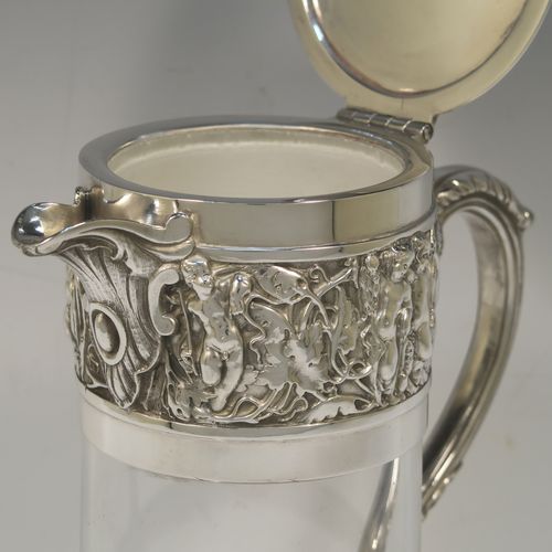 A very handsome Antique Victorian Silver Plated and hand-cut crystal claret jug, having an ornate  Bacchus style round mount with hand-chased figural work, a cast side handle with a plain round security ring, a hinged lid with a cast rampant lion and shield finial, together with a hand-cut crystal round body with straight sides and a tucked under belly above a flat star-cut base. Made by Hukin and Heath  of Sheffield in ca. 1880. The dimensions of this fine hand-made antique silver-plated and crystal claret jug are height 26 cms (10.25 inches), and length 16 cms (6.3 inches).  