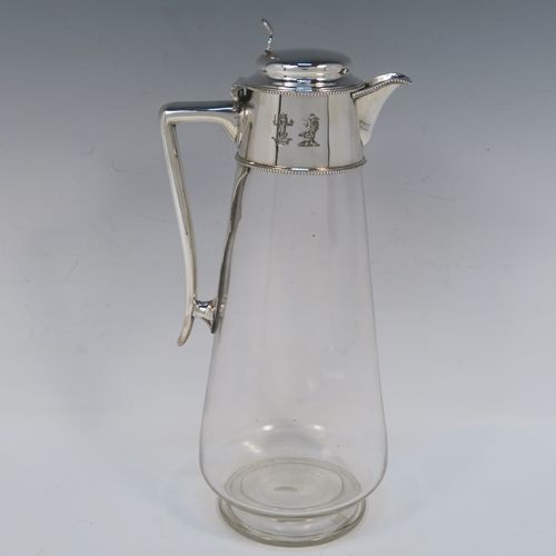 A very elegant Antique Victorian Silver Plated and hand-cut crystal claret jug, having a plain round mount with applied bead-edged borders, a plain side handle with a vertical strengthening strut, a hinged domed lid with a plain thumb-piece, together with a hand-cut crystal round body with straight tapering sides and a tucked under belly above a pedestal foot. This handsome silver-plated and crystal claret jug was made in ca. 1890. The dimensions of this fine hand-made antique silver-plated and crystal claret jug are height 28 cms (11 inches), and length 12.5 cms (5 inches). Please note that this item is crested.   