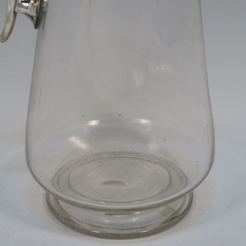 A very elegant Antique Victorian Silver Plated and hand-cut crystal claret jug, having a plain round mount with applied bead-edged borders, a plain side handle with a vertical strengthening strut, a hinged domed lid with a plain thumb-piece, together with a hand-cut crystal round body with straight tapering sides and a tucked under belly above a pedestal foot. This handsome silver-plated and crystal claret jug was made in ca. 1890. The dimensions of this fine hand-made antique silver-plated and crystal claret jug are height 28 cms (11 inches), and length 12.5 cms (5 inches). Please note that this item is crested.   