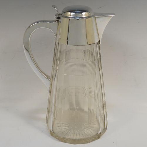 A very handsome Antique Sterling Silver and hand-cut crystal claret jug, having a plain oval mount and spout, a hinged domed lid with a thumb-piece, a plain scroll handle, together with a hand-cut round and panelled crystal body with reeded bands and star-cut base. This beautiful silver and crystal claret jug was made by John Round of Birmingham in 1919. The dimensions of this fine hand-made silver and crystal claret jug are height 24 cms (9.5 inches), and length 16.5 cms (6.5 inches).   