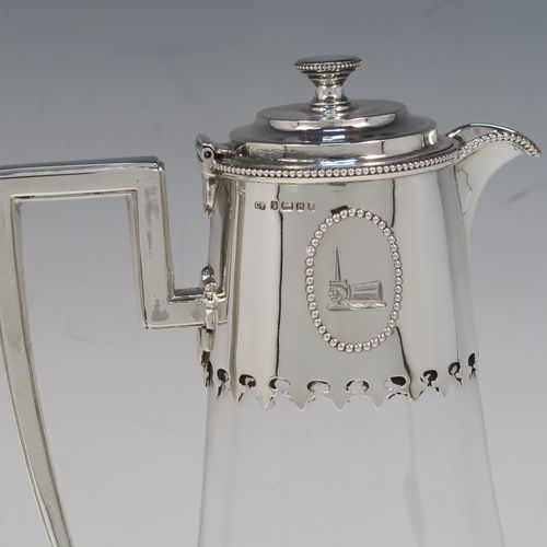 A very elegant Antique Victorian Sterling Silver and hand-cut crystal claret jug, having a plain round mount with applied bead-edged borders, a plain square cross-section side handle, a hinged stepped lid with a cast round finial, together with a hand-cut crystal round body with straight tapering sides and a tucked under belly above a pedestal foot. This handsome silver and crystal claret jug was made by Charles Favell of Sheffield in 1875. The dimensions of this fine hand-made antique silver and crystal claret jug are height 28 cms (11 inches), and length 13.5 cms (5.25 inches). Please note that this item has two oval cartouches with bead borders one of which is  engraved with a part crest.   