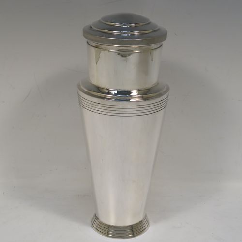 A very stylish and handsome Silver-Plated Art Deco cocktail shaker, having a plain round body with tapering sides and reeded decoration, a pull-off round stepped lid, and a central removable strainer section with loop handle. This elegant silver-plated cocktail shaker was made by Mappin and Webb of Sheffield in ca. 1930. The dimensions of this fine hand-made silver plated cocktail shaker are height 23 cms (9 inches), and diameter at widest point is 9 cms (3.5 inches).   