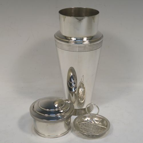 A very stylish and handsome Silver-Plated Art Deco cocktail shaker, having a plain round body with tapering sides and reeded decoration, a pull-off round stepped lid, and a central removable strainer section with loop handle. This elegant silver-plated cocktail shaker was made by Mappin and Webb of Sheffield in ca. 1930. The dimensions of this fine hand-made silver plated cocktail shaker are height 23 cms (9 inches), and diameter at widest point is 9 cms (3.5 inches).   