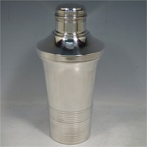 A very handsome Art Deco style Silver-Plated cocktail shaker, having a plain round body with tapering sides, with a pull-off lid and a strainer section, together with a lower band of hand-chased reeded decoration. Made in ca. 1930. The dimensions of this fine hand-made silver plated cocktail shaker are height 21 cms (8.25 inches), diameter at widest point 10 cms (4 inches).   