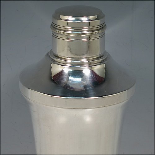 A very handsome Art Deco style Silver-Plated cocktail shaker, having a plain round body with tapering sides, with a pull-off lid and a strainer section, together with a lower band of hand-chased reeded decoration. Made in ca. 1930. The dimensions of this fine hand-made silver plated cocktail shaker are height 21 cms (8.25 inches), diameter at widest point 10 cms (4 inches).   