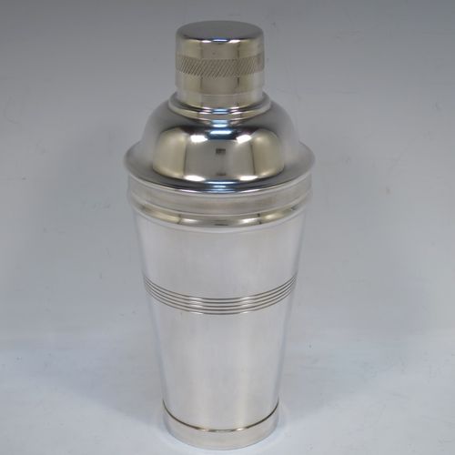 A very stylish and handsome Silver-Plated Art Deco cocktail shaker, having a plain round body with tapering sides, with reeded and engine-turned decoration, a pull-off round lid, and a central removable strainer section. Made in ca. 1930. The dimensions of this fine hand-made silver plated cocktail shaker are height 21.5 cms (8.5 inches), and diameter at widest point is 9 cms (3.5 inches).  