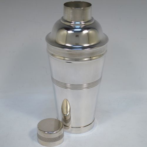 A very stylish and handsome Silver-Plated Art Deco cocktail shaker, having a plain round body with tapering sides, with reeded and engine-turned decoration, a pull-off round lid, and a central removable strainer section. Made in ca. 1930. The dimensions of this fine hand-made silver plated cocktail shaker are height 21.5 cms (8.5 inches), and diameter at widest point is 9 cms (3.5 inches).  