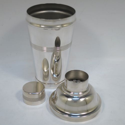 A very stylish and handsome Silver-Plated Art Deco cocktail shaker, having a plain round body with tapering sides, with reeded and engine-turned decoration, a pull-off round lid, and a central removable strainer section. Made in ca. 1930. The dimensions of this fine hand-made silver plated cocktail shaker are height 21.5 cms (8.5 inches), and diameter at widest point is 9 cms (3.5 inches).  