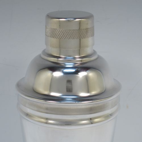 A very stylish and handsome Silver-Plated Art Deco cocktail shaker, having a plain round body with tapering sides, with reeded and engine-turned decoration, a pull-off round lid, and a central removable strainer section. Made in ca. 1930. The dimensions of this fine hand-made silver plated cocktail shaker are height 21.5 cms (8.5 inches), and diameter at widest point is 9 cms (3.5 inches).  