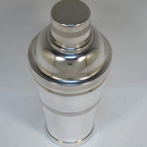 A very stylish and handsome Silver-Plated Art Deco cocktail shaker, having a plain round body with tapering sides, with reeded and engine-turned decoration, a pull-off round lid, and a central removable strainer section. Made in ca. 1930. The dimensions of this fine hand-made silver plated cocktail shaker are height 21.5 cms (8.5 inches), and diameter at widest point is 9 cms (3.5 inches).  