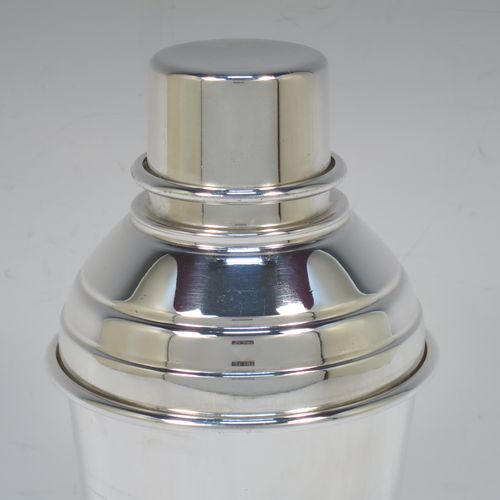 A very stylish Silver-Plated Art Deco cocktail shaker, having a plain round body with tapering sides and hand-chased bands of reeded decoration, a plain round and flat top pull-off lid, and a central removable strainer section. Made in ca. 1930 in Sheffield, England. The dimensions of this fine hand-made silver plated cocktail shaker are height 20 cms (8 inches), and diameter at widest point is 9 cms (3.5 inches).  