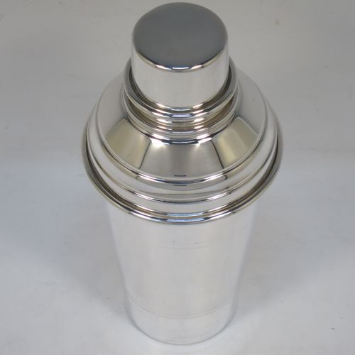 A very stylish Silver-Plated Art Deco cocktail shaker, having a plain round body with tapering sides and hand-chased bands of reeded decoration, a plain round and flat top pull-off lid, and a central removable strainer section. Made in ca. 1930 in Sheffield, England. The dimensions of this fine hand-made silver plated cocktail shaker are height 20 cms (8 inches), and diameter at widest point is 9 cms (3.5 inches).  