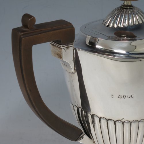 An Antique Victorian Sterling Silver coffee pot, in a Queen Anne style, having an oval tapering body with hand-chased half-fluted decoration, a wooden handle, a hinged lid with an invisible flat hinge and wooden finial, and all sitting on a pedestal foot. Made by Charles Stuart Harris of London in 1885. The dimensions of this fine hand-made antique silver coffee pot are length 22 cms (8.5 inches), height 21 cms (8.25 inches), and it weighs approx. 340g (11 troy ounces).   