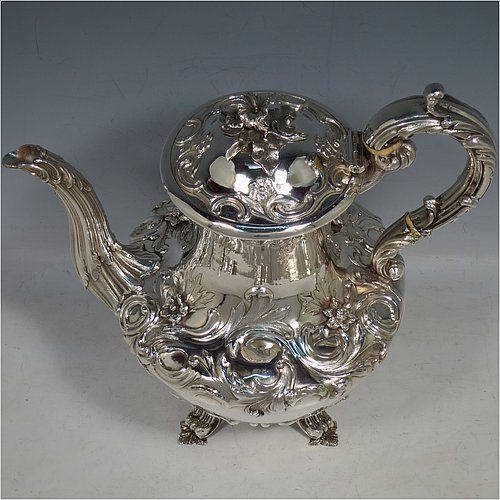 An Antique Georgian William IV Sterling Silver hand-chased coffee pot, having a round hand-chased bellied body with floral and scroll decoration, a hinged lid with original cast flower finial, an insulated silver handle with anthemion thumb-piece, and sitting on cast floral and scroll feet. Made by the Barnard Brothers of London in 1832. The dimensions of this fine hand-made antique silver coffee pot are height 25 cms (9.75 inches), length 25.5 cms (10 inches), and it weighs approx. 978g (31.5 troy ounces).   