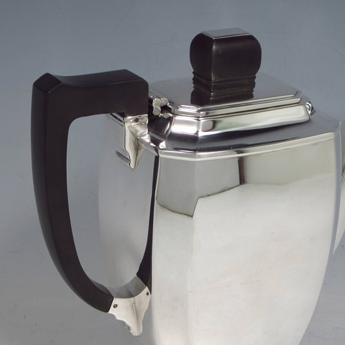 A Sterling silver Art Deco style coffee pot, having very plain panelled body with tapering sides, a wooden handle, a hinged lid with matching finial, and all sitting on a collet foot. Made by Mappin & Webb of Sheffield in 1950. The dimensions of this fine hand-made silver coffee pot are length 20 cms (8 inches), height 19 cms (7.5 inches), and it weighs approx. 600g (19.4 troy ounces).   