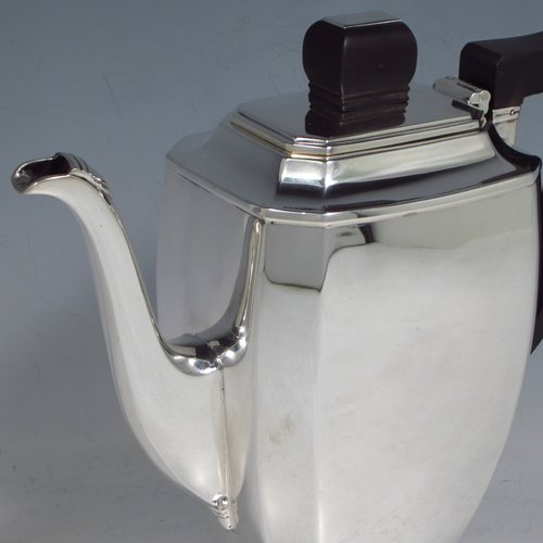 A Sterling silver Art Deco style coffee pot, having very plain panelled body with tapering sides, a wooden handle, a hinged lid with matching finial, and all sitting on a collet foot. Made by Mappin & Webb of Sheffield in 1950. The dimensions of this fine hand-made silver coffee pot are length 20 cms (8 inches), height 19 cms (7.5 inches), and it weighs approx. 600g (19.4 troy ounces).   