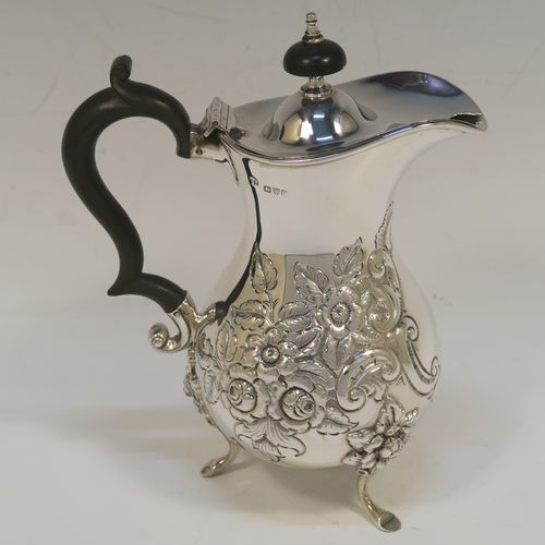 A small but very pretty Antique Victorian  Sterling Silver coffee pot, having a round hand-chased bellied body with hand-chased floral decoration, a domed hinged lid with a wooden finial, a matching black-stained wooden scroll handle, and all sitting on three cast feet with floral shoulders. This beautiful small silver coffee pot was made by William Aitken of Chester in 1899. The dimensions of this fine hand-made antique silver coffee pot are height 17 cms (6.75 inches), length 14 cms (5.5 inches), and it weighs approx. 350g (11 troy ounces).   