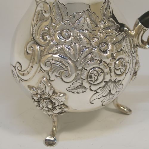 A small but very pretty Antique Victorian  Sterling Silver coffee pot, having a round hand-chased bellied body with hand-chased floral decoration, a domed hinged lid with a wooden finial, a matching black-stained wooden scroll handle, and all sitting on three cast feet with floral shoulders. This beautiful small silver coffee pot was made by William Aitken of Chester in 1899. The dimensions of this fine hand-made antique silver coffee pot are height 17 cms (6.75 inches), length 14 cms (5.5 inches), and it weighs approx. 350g (11 troy ounces).   