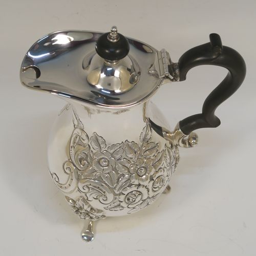 A small but very pretty Antique Victorian  Sterling Silver coffee pot, having a round hand-chased bellied body with hand-chased floral decoration, a domed hinged lid with a wooden finial, a matching black-stained wooden scroll handle, and all sitting on three cast feet with floral shoulders. This beautiful small silver coffee pot was made by William Aitken of Chester in 1899. The dimensions of this fine hand-made antique silver coffee pot are height 17 cms (6.75 inches), length 14 cms (5.5 inches), and it weighs approx. 350g (11 troy ounces).   