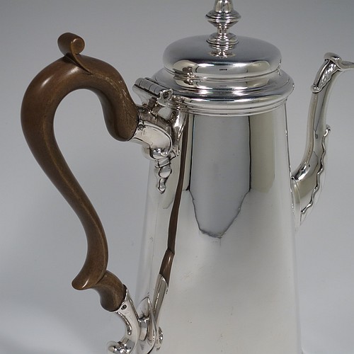 An Antique Georgian Sterling Silver George II coffee pot, having a plain round body with straight tapering sides, a hinged cushion style lid with cast finial, a curved spout with an applied anthemion leaf, a hand-carved wooden scroll handle, and all sitting on a collet foot. Made by Edward Vincent of London in 1738. The dimensions of this fine hand-made antique silver coffee pot are length 21 cms (8.25 inches), height 23.5 cms (9.25 inches), and it weighs approx. 845g (27 troy ounces). Please note that this item is engraved with a full armorial crest on one side.   