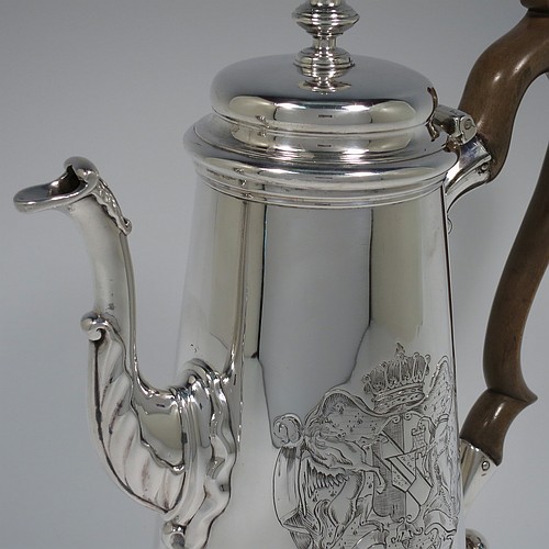 An Antique Georgian Sterling Silver George II coffee pot, having a plain round body with straight tapering sides, a hinged cushion style lid with cast finial, a curved spout with an applied anthemion leaf, a hand-carved wooden scroll handle, and all sitting on a collet foot. Made by Edward Vincent of London in 1738. The dimensions of this fine hand-made antique silver coffee pot are length 21 cms (8.25 inches), height 23.5 cms (9.25 inches), and it weighs approx. 845g (27 troy ounces). Please note that this item is engraved with a full armorial crest on one side.   