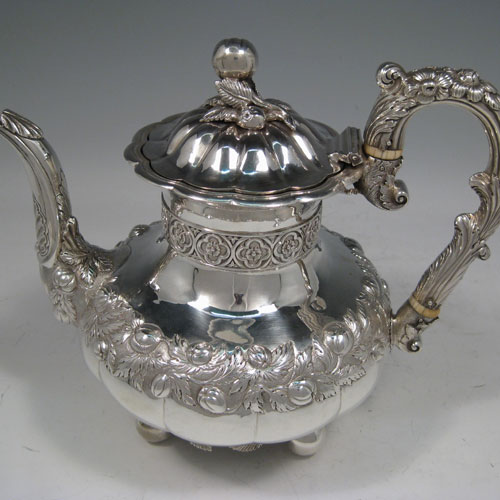 Antique Georgian sterling silver hand-chased coffee pot, having a round hand-chased baluster body with floral decoration, a hinged lid with melon fluting and original cast finial, an insulated silver handle, and sitting on four ball feet with applied cast leaves. Made by one of the most important English silversmiths from the late Georgian period, Edward Farrell, of London in 1828. The dimensions of this fine hand-made silver coffee pot are height 21 cms (8.25 inches), length 25.5 cms (10 inches), and it weighs approx. 930g (30 troy ounces).