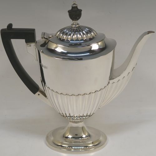 A pretty Antique Victorian Sterling Silver coffee pot, in a Queen Anne style, having an oval tapering body with hand-chased half-fluted decoration, a black wooden handle, a hinged lid with an invisible flat hinge and wooden finial, and all sitting on a pedestal foot. This beautiful antique silver coffee pot was made by Charles Stuart Harris of London in 1899. The dimensions of this fine hand-made antique silver coffee pot are length 22.5 cms (8.75 inches), height 23.5 cms (9.25 inches), and it weighs approx. 450g (14.5 troy ounces)   