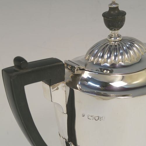 A pretty Antique Victorian Sterling Silver coffee pot, in a Queen Anne style, having an oval tapering body with hand-chased half-fluted decoration, a black wooden handle, a hinged lid with an invisible flat hinge and wooden finial, and all sitting on a pedestal foot. This beautiful antique silver coffee pot was made by Charles Stuart Harris of London in 1899. The dimensions of this fine hand-made antique silver coffee pot are length 22.5 cms (8.75 inches), height 23.5 cms (9.25 inches), and it weighs approx. 450g (14.5 troy ounces)   