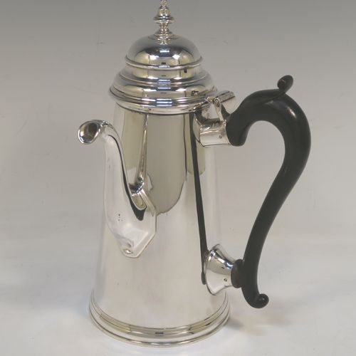 A large and very handsome Antique Edwardian Sterling Silver George II style side-handled coffee pot, having a plain round body with straight tapering sides, a hinged domed lid with cast urn-shaped finial, a curved and panelled spout, a hand-carved wooden scroll handle, and all sitting on a flat base. This elegant silver coffee-pot was made by D. and J. Welby of London in 1910. The dimensions of this fine hand-made antique silver side-handled coffee pot are length 13.5 cms (5.25 inches), height 23.5 cms (9.25 inches), and it weighs approx. 750g (24 troy ounces).  