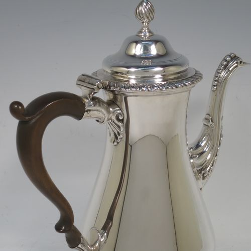 A very handsome Antique Georgian Sterling Silver coffee pot, having a plain round bellied body, with applied gadroon borders, a wooden scroll handle, a flame knop finial, and anthemion leaf decorated spout. Made by William Grundy London in 1775. The dimensions of this fine hand-made antique silver coffee pot are height 26 cms (10.25 inches), length 22 cms (8.75 inches), and it weighs approx. 800g (25.8 troy ounces).    